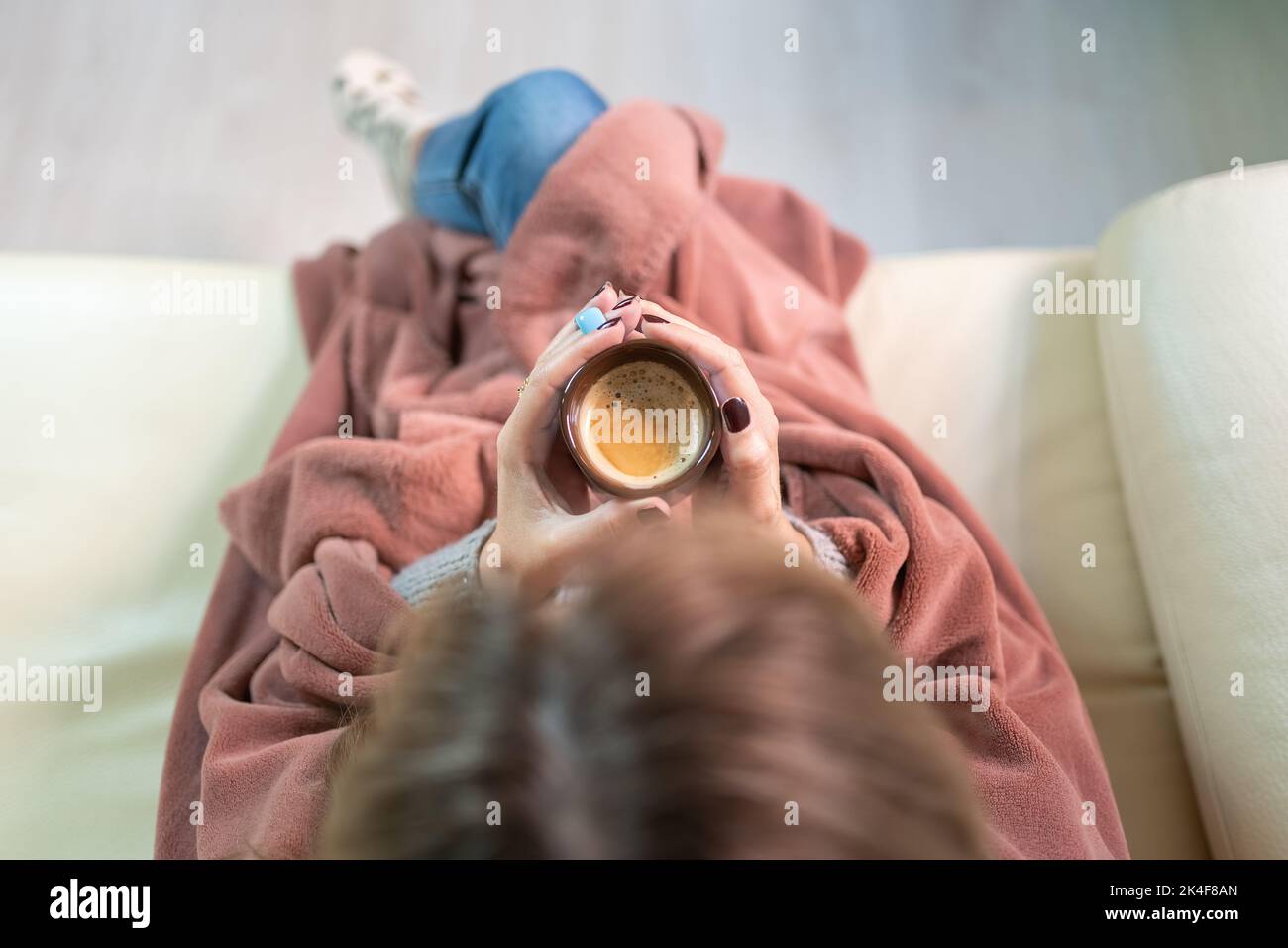 Femme qui chauffe les mains avec une tasse de café chaud tout en appréciant la chaleur de la maison au milieu de l'hiver. Banque D'Images