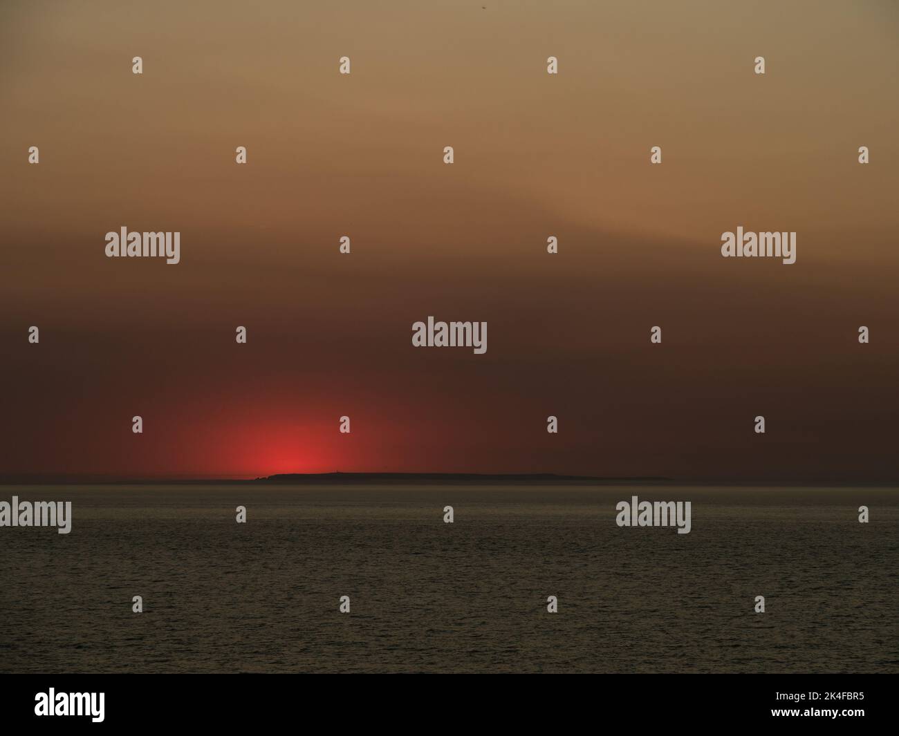 Coucher de soleil rouge sur Lundy Island, vue depuis Westward Ho. Le soleil vient de se coucher sous l'horizon. Banque D'Images