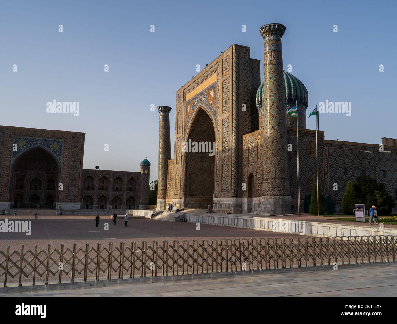 Sherdor Madrassa, dans le complexe du Registan, présente une arche en mosaïque bleue complexe avec des rayons de soleil frappant les sommets au coucher du soleil, Samarkand Banque D'Images