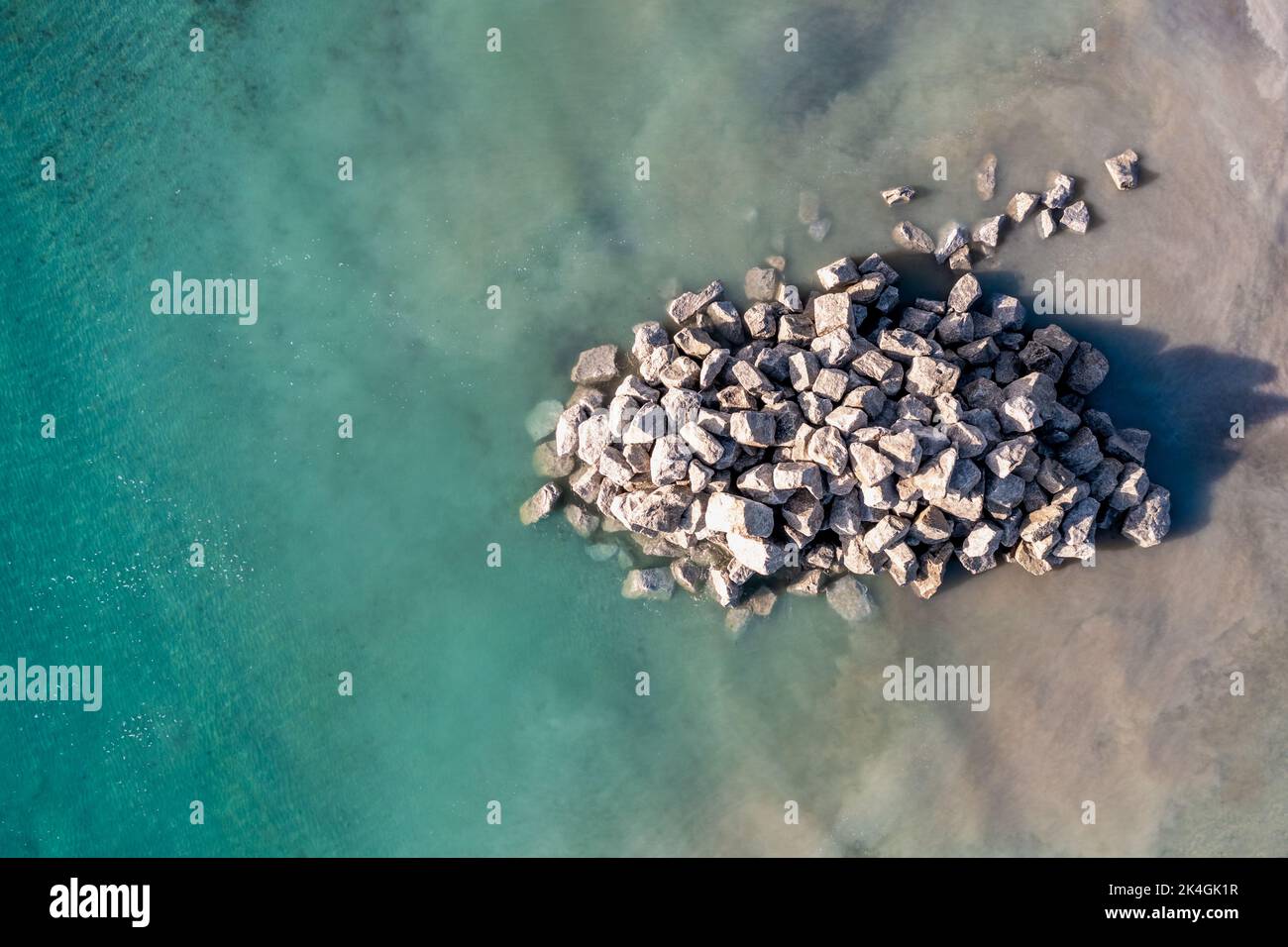Vue aérienne directement au-dessus d'un tas de rochers utilisés pour réparer les défenses côtières et les murs de mer d'une carrière et dans l'océan sur une plage de Cornouailles Banque D'Images