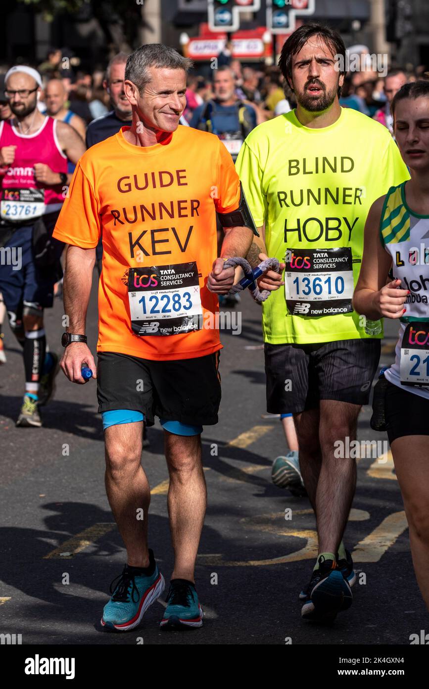 Coureur aveugle avec guide, course au TCS London Marathon 2022, sur Tower Hill Road, City of London, Royaume-Uni. Hoby Allen et Kevin Drodge Banque D'Images