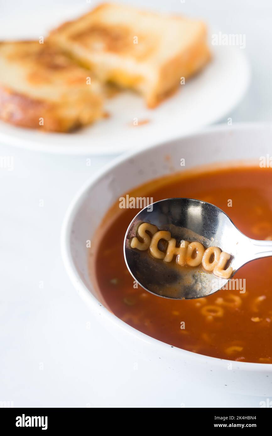 Soupe à l'alphabet avec le mot école écrit dans la cuillère. Banque D'Images