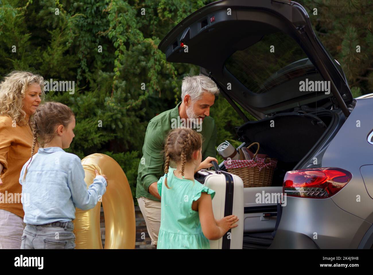 Famille avec de petits enfants qui chargent la voiture et qui attendent de charger la voiture avant de partir en vacances. Banque D'Images