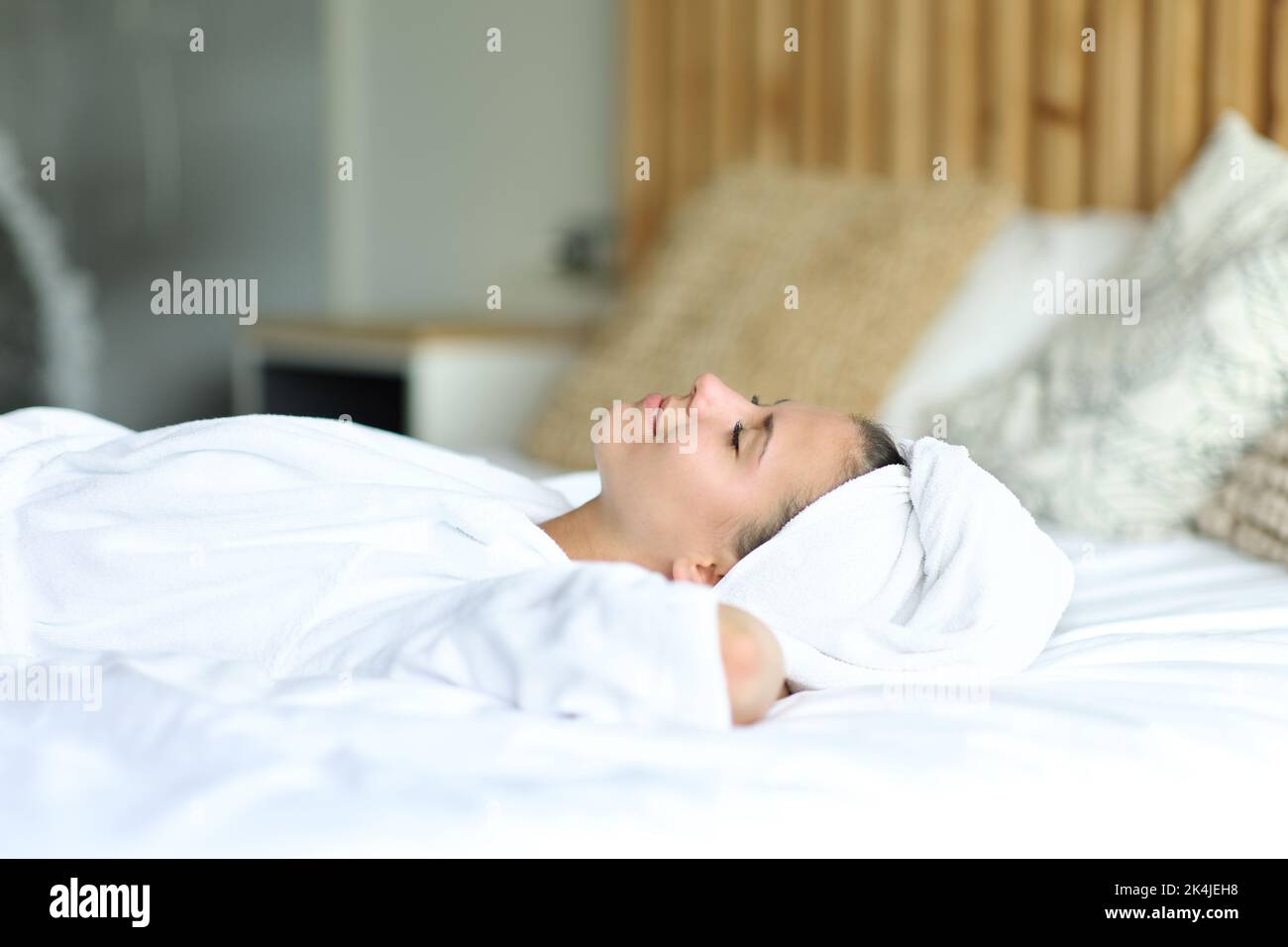 Une femme heureuse se reposant sur le lit après avoir pris la douche à la maison Banque D'Images