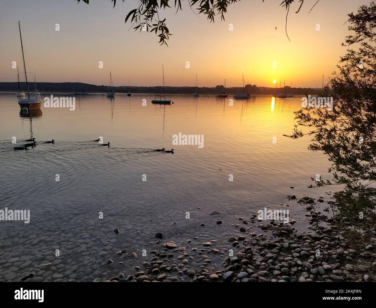 Une belle scène du lac Ammersee et des bateaux à l'horizon en Allemagne sous le ciel du coucher du soleil Banque D'Images