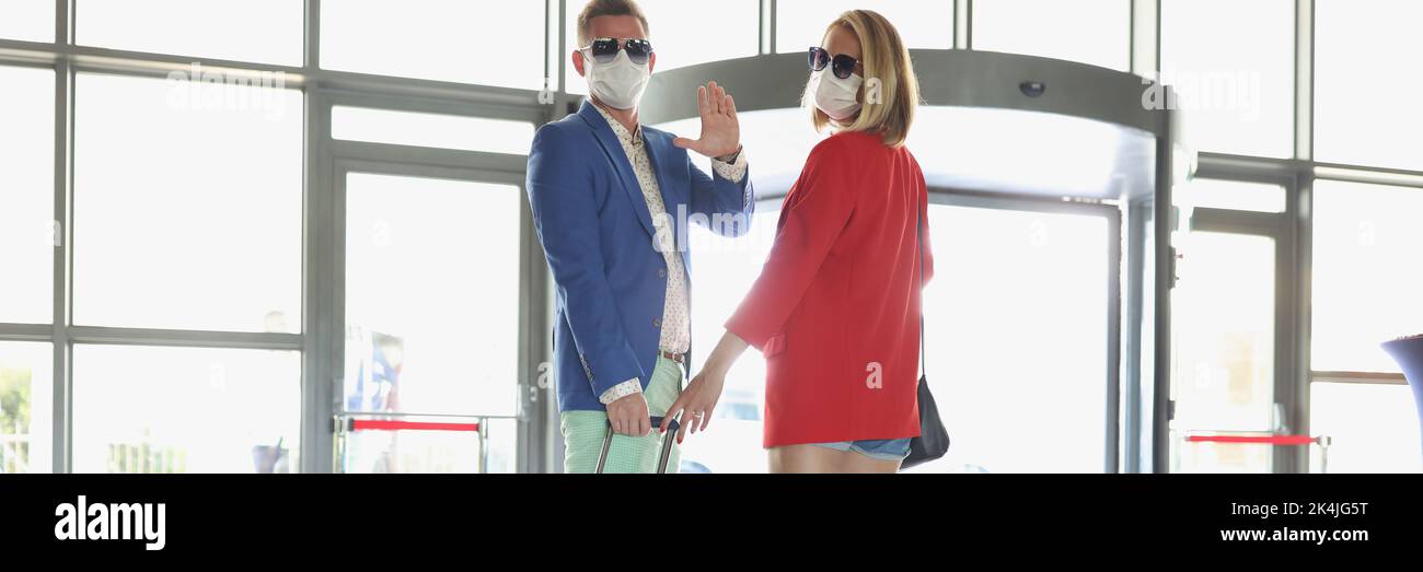 Couple vêtu de costumes de luxe avec une valise à vagues Au revoir avant de prendre l'avion en vacances Banque D'Images