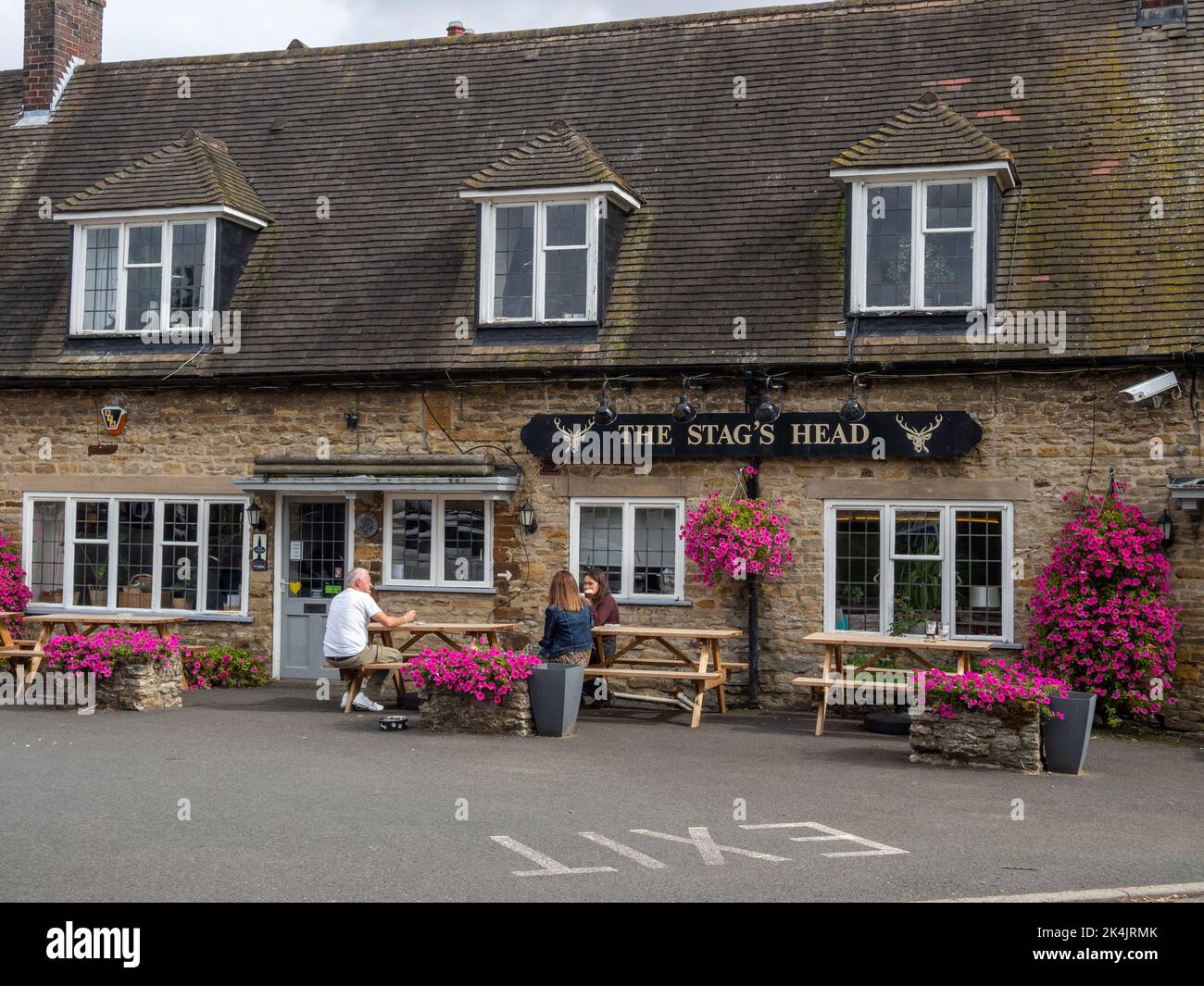 Le pub Stags Head, avec des paniers suspendus colorés, dans le village de Great Doddington, Northamptonshire, Royaume-Uni Banque D'Images