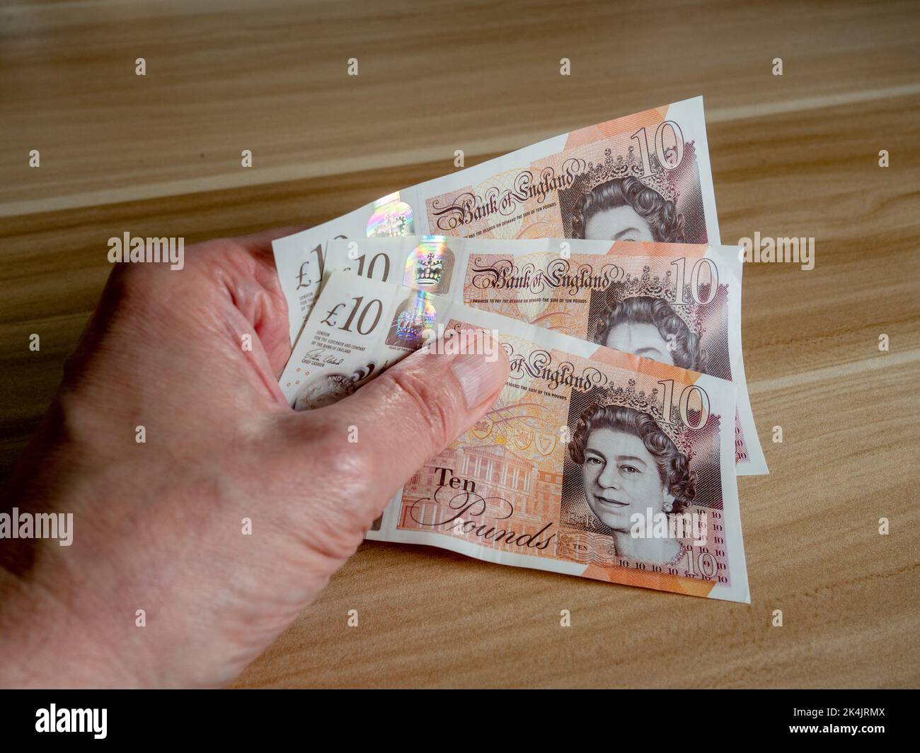 Main de l'homme tenant trois notes de £10 avec la tête de la reine Elizabeth II - une des nombreuses choses qui nécessitent un amendement après sa mort. Banque D'Images
