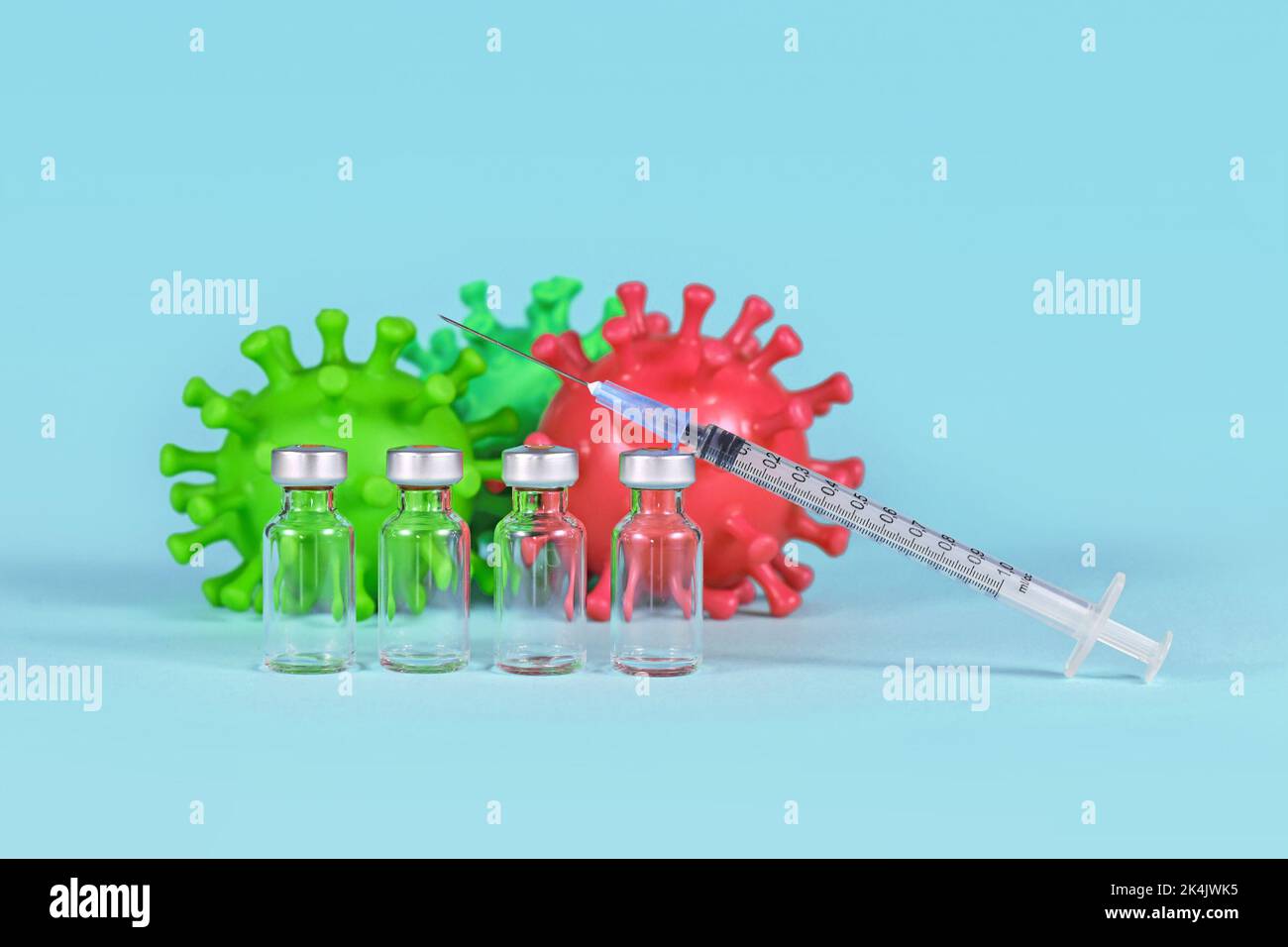 Vaccin de rappel Corona concept avec 4 flacons avec seringue et modèles de virus en arrière-plan Banque D'Images