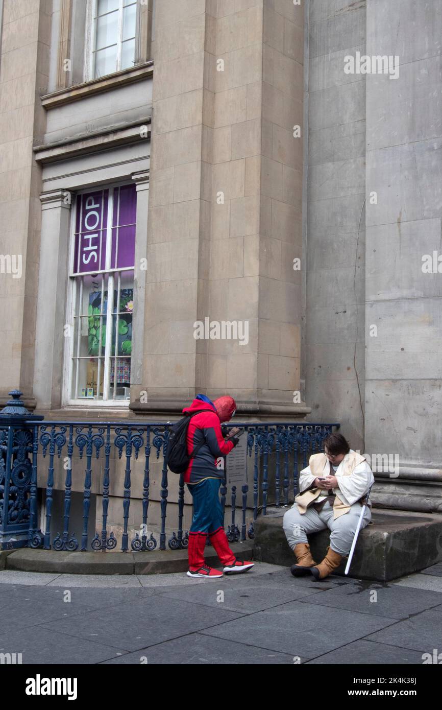 Spider man et OBI-wan Kenobi vérifient leurs téléphones, à l'extérieur de la Gallery of Modern Art, Glasgow, Glasgow, Écosse, Royaume-Uni Banque D'Images