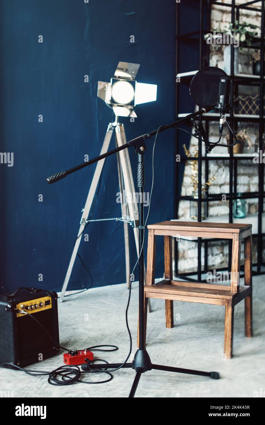 microphone condensateur studio avec filtre pop et support anti-vibration pour l'enregistrement en direct. Mur bleu, haut-parleur et lumière décorative sur fond Banque D'Images