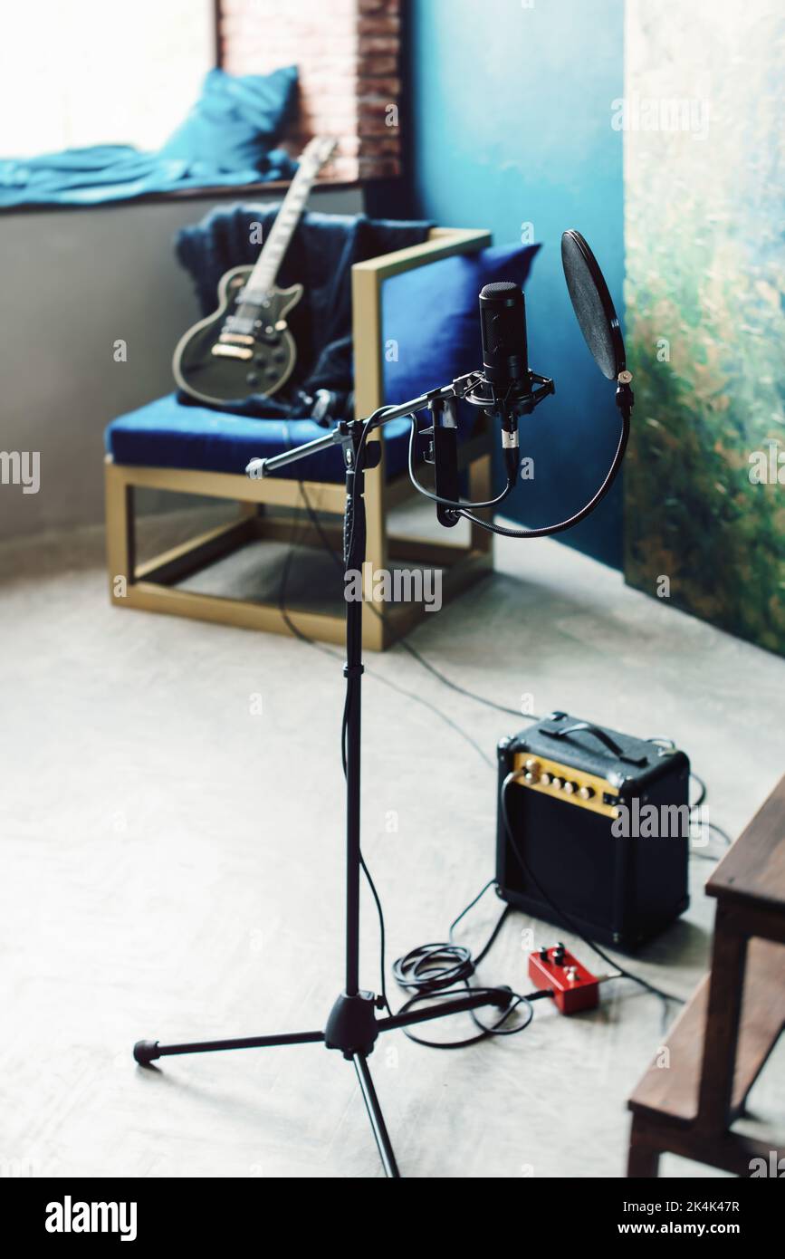 microphone condensateur studio avec filtre pop et support anti-vibration pour l'enregistrement en direct. Mur bleu, haut-parleur et guitare sur fond Banque D'Images