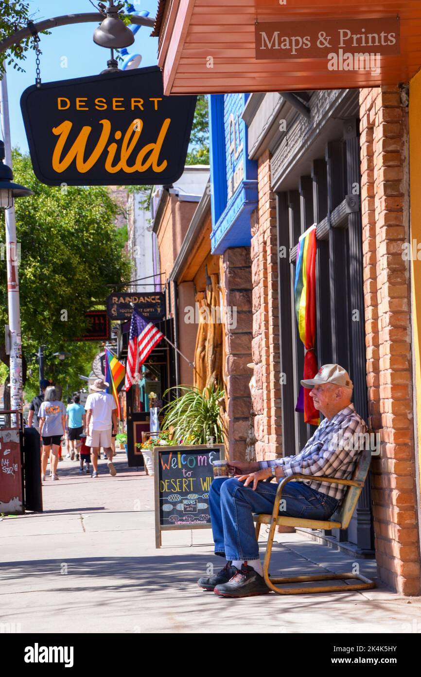 Un vieil homme dans une chemise à carreaux est assis dans une chaise à l'ombre sur la rue principale de Moab, dans l'Utah, aux États-Unis Banque D'Images