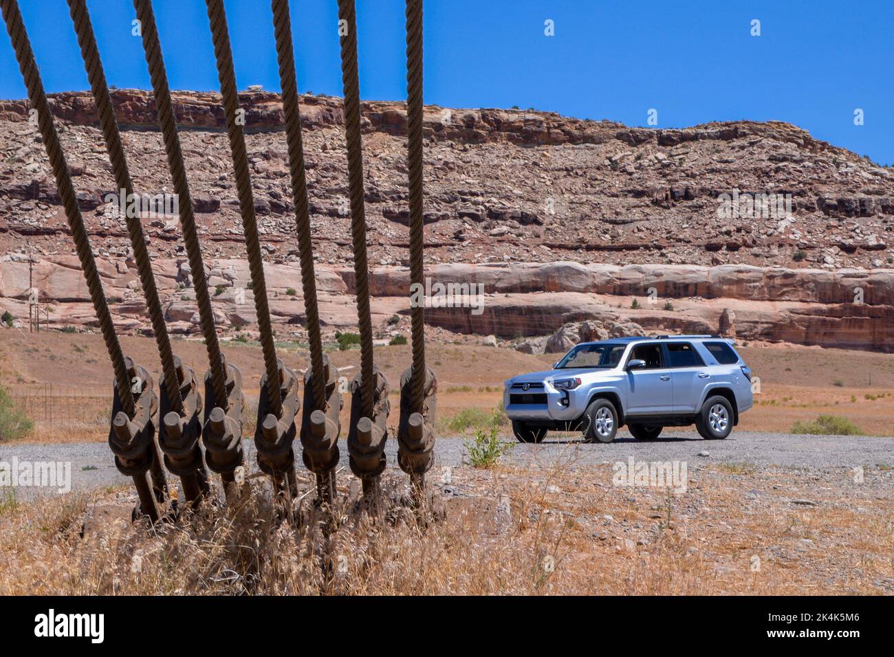 Un véhicule utilitaire sport argenté est stationné près des câbles de câble robustes qui se connectent aux points d'ancrage de masse du pont de suspension Dewey, près de Cisco, dans l'Utah, aux États-Unis Banque D'Images