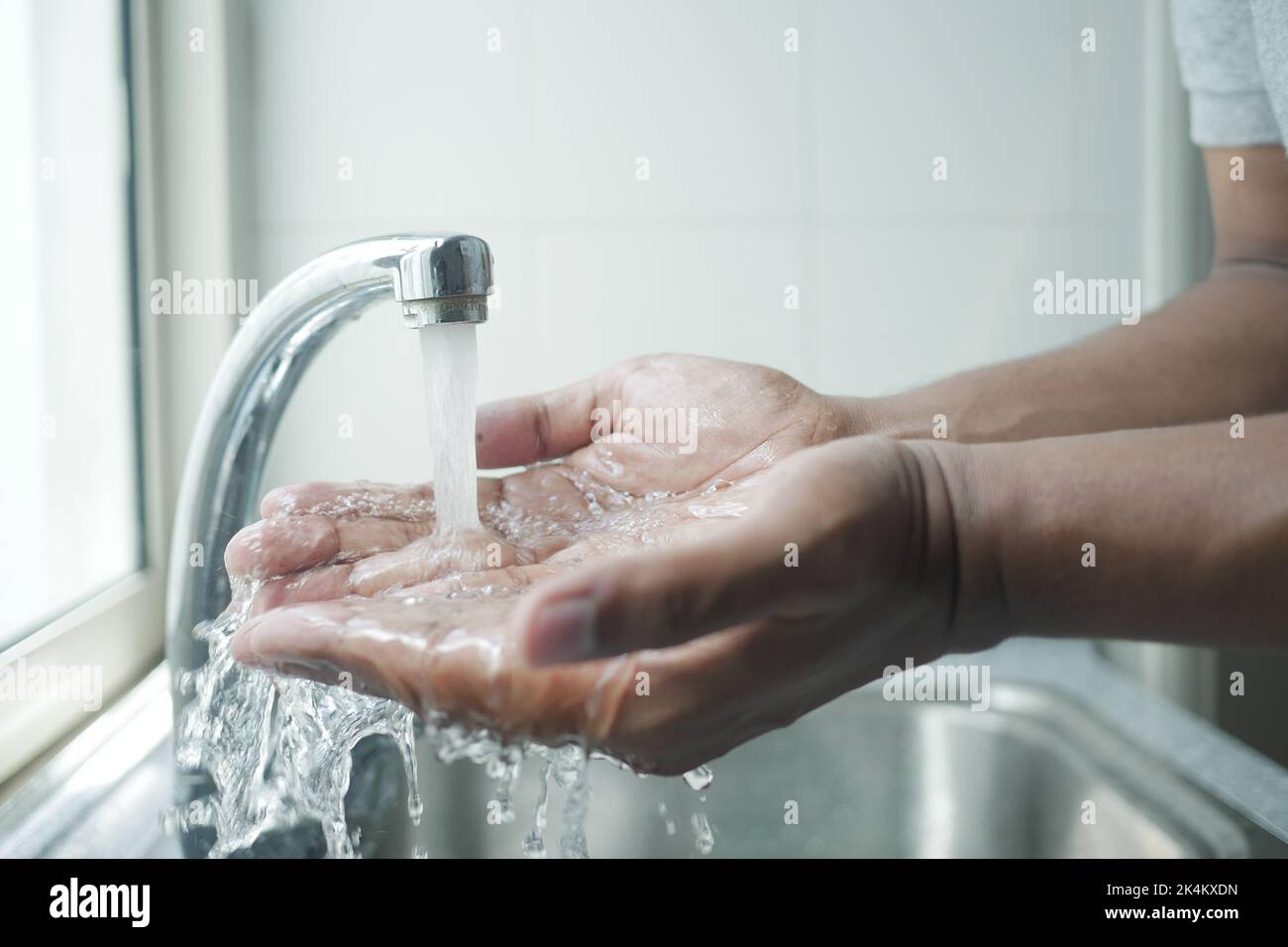 jeune homme se lavant les mains à l'eau chaude Banque D'Images