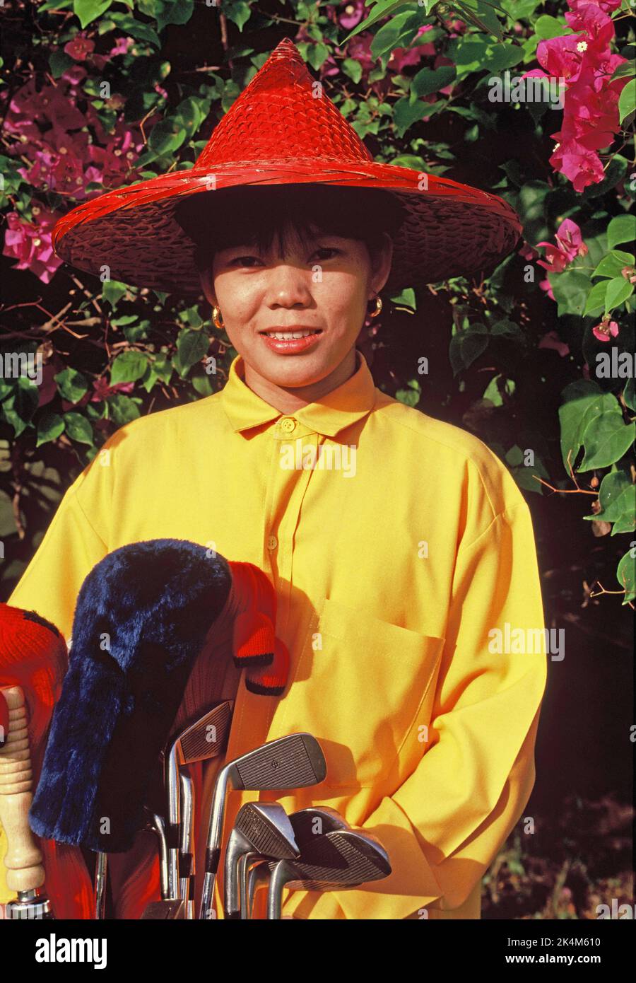 Thaïlande. Nakhon Pathom. Jardin de roses. Portrait extérieur de la femme thaïlandaise caddie avec des clubs de golf. Banque D'Images