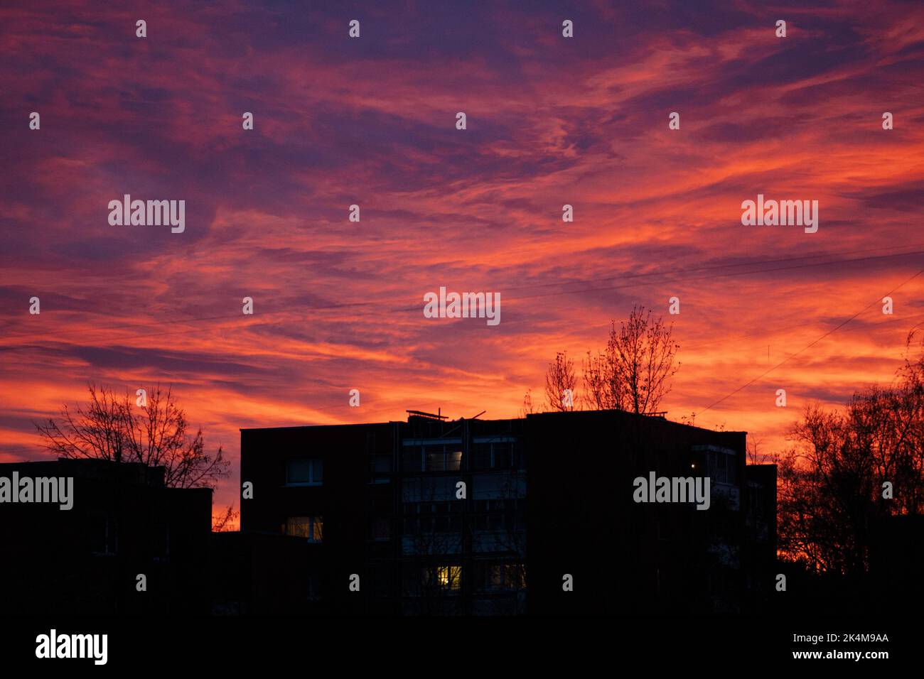 Magnifique coucher de soleil rouge et violet sur les bâtiments de la ville avec des bâtiments et des arbres silhouette Banque D'Images