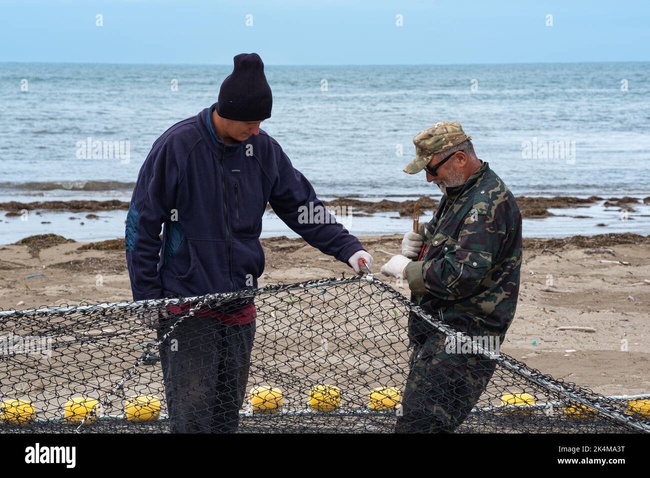 Lagunnoe, Russie - 01 août 2022: Les pêcheurs vérifient et réparent le filet de pêche sur la rive Banque D'Images