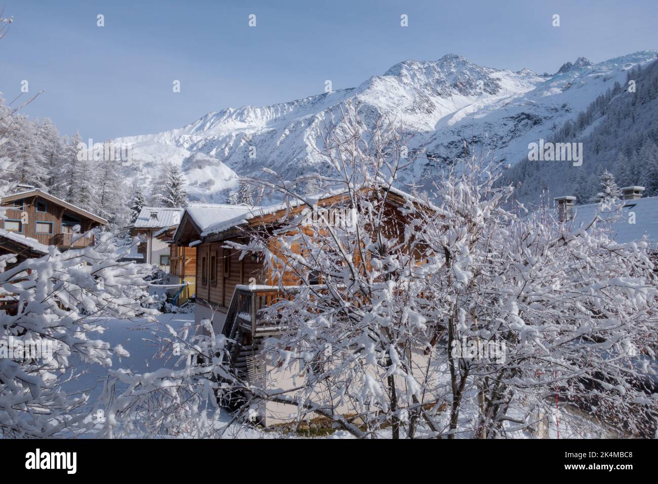 Chalets de montagne dans un petit hameau au-dessous de la crête alpine, couverts de neige fraîche dans la vallée de Chamonix en France Banque D'Images