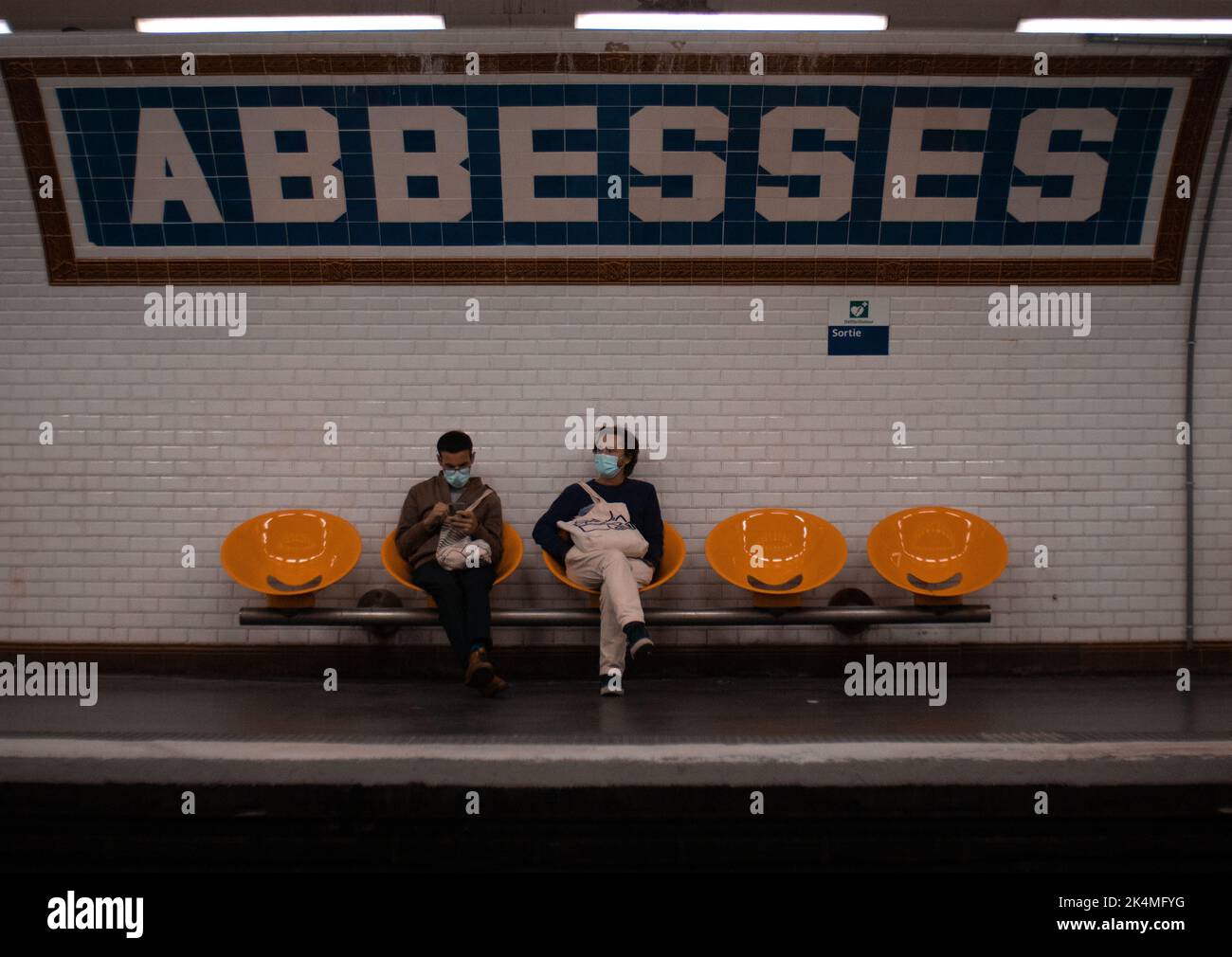Deux hommes dans des masques assis sur les chaises et attendant le métro à Paris, France Banque D'Images