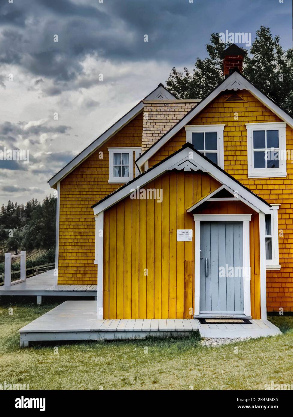 Une vue verticale d'une maison de campagne en bois scandinave avec des murs jaunes, ciel sombre Banque D'Images