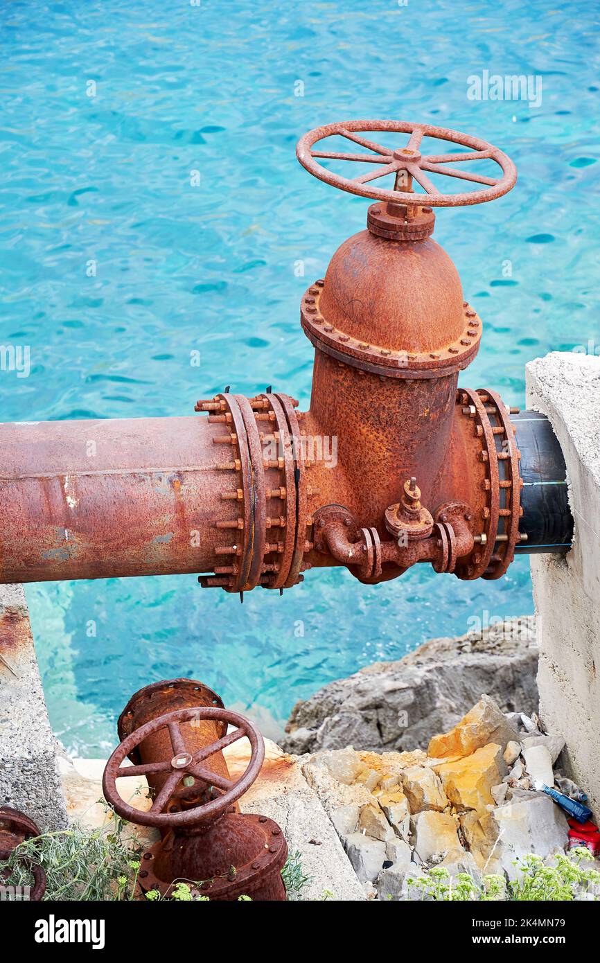 Les tuyaux et la valve sur la côte de mer sont tous de la rouille. Concept de pollution de l'eau et de la nature Banque D'Images