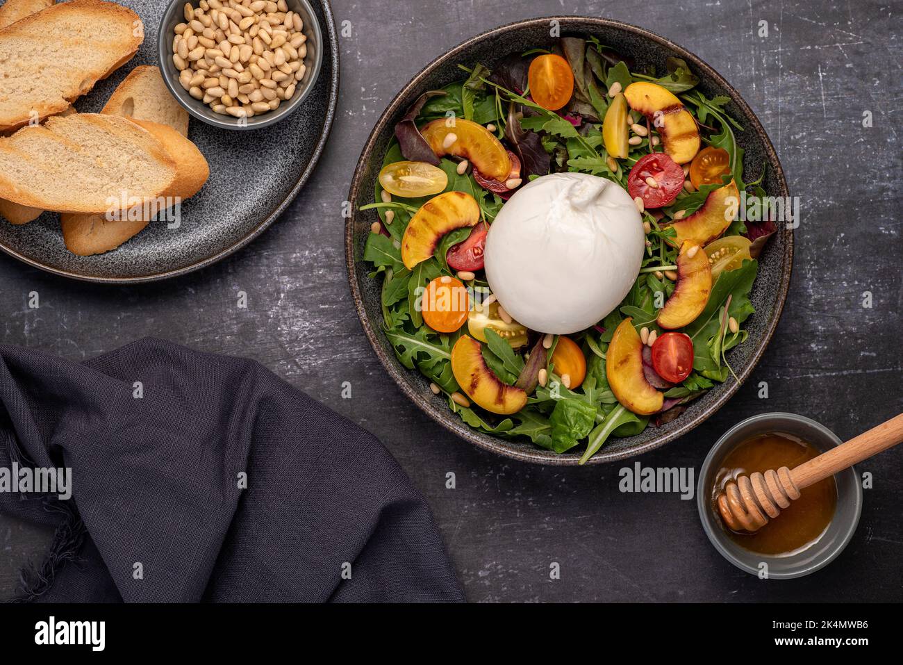 Photographie de nourriture de salade avec burrata, tomate, feuilles, pêche grillée Banque D'Images