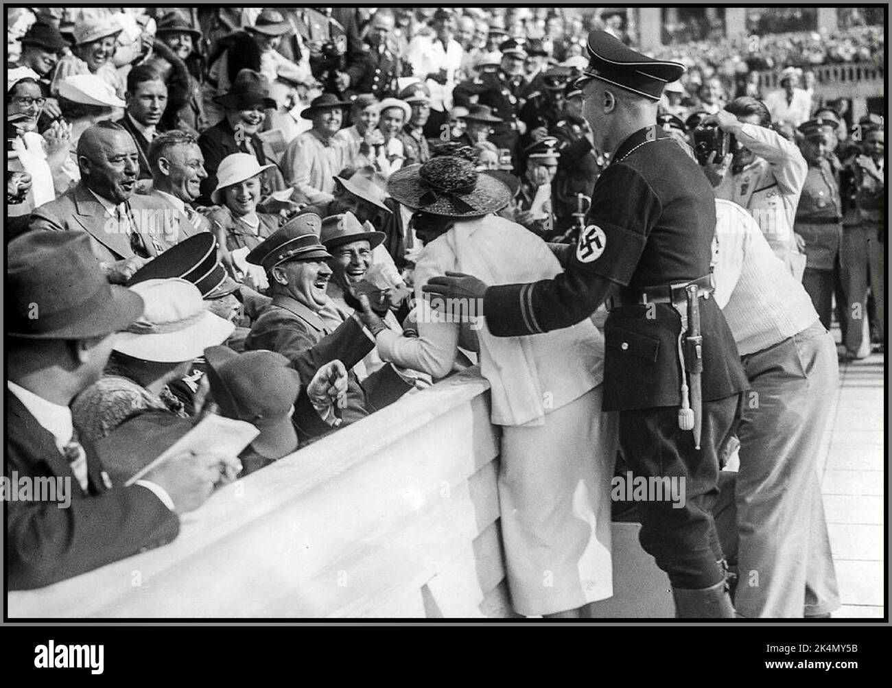 JEUX OLYMPIQUES DE BERLIN HITLER Adolf Hitler rit et réagit à une tentative de baiser de la femme américaine excitée aux Jeux olympiques de Berlin en Allemagne nazie, 1936. Banque D'Images