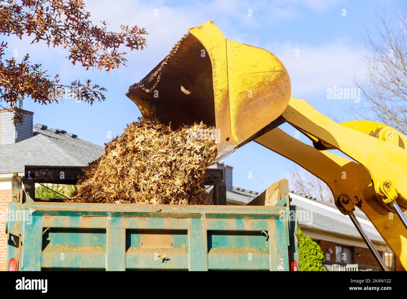 Il s'agit d'une pratique courante en automne lorsque les employés municipaux retirent les feuilles mortes à l'aide d'une pelle hydraulique et d'un camion dans le voisinage des maisons Banque D'Images