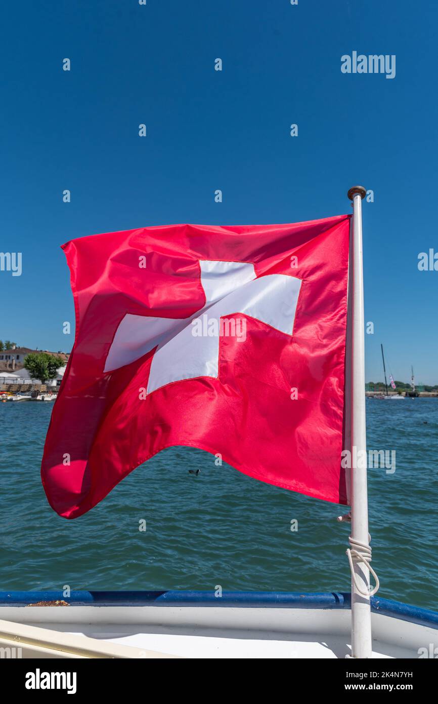 Photo portrait du drapeau suisse qui flotte dans le vent depuis un bateau sur le lac Léman. Banque D'Images