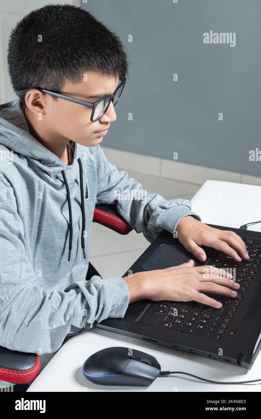 Adolescent garçon à la maison école étudier chambre bureau pc ordinateur lunettes assis regardant les devoirs Banque D'Images