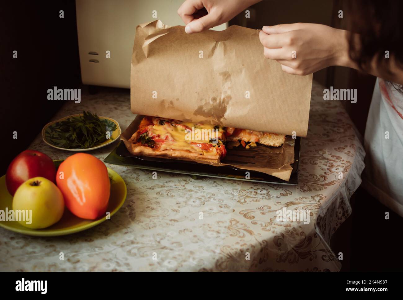 Une fille lève le papier de la pizza maison en prévision Banque D'Images