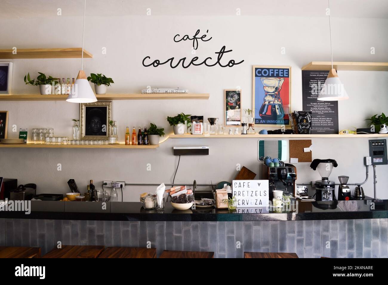 intérieur de la cafétéria avec comptoir de bar en bois, étagères et planche avec tasse de café dessinée, comptoir en granit, étagères à l'arrière, mur blanc Banque D'Images