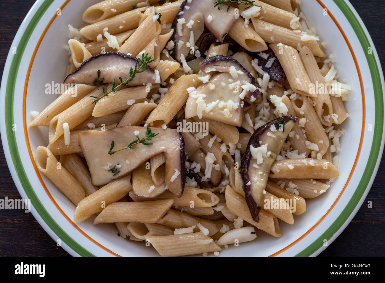 Pâtes Penne aux boletus de porcini, aux champignons, au parmesan, au romarin et à l'ail sur l'assiette. Vue de dessus sur une table en bois Banque D'Images