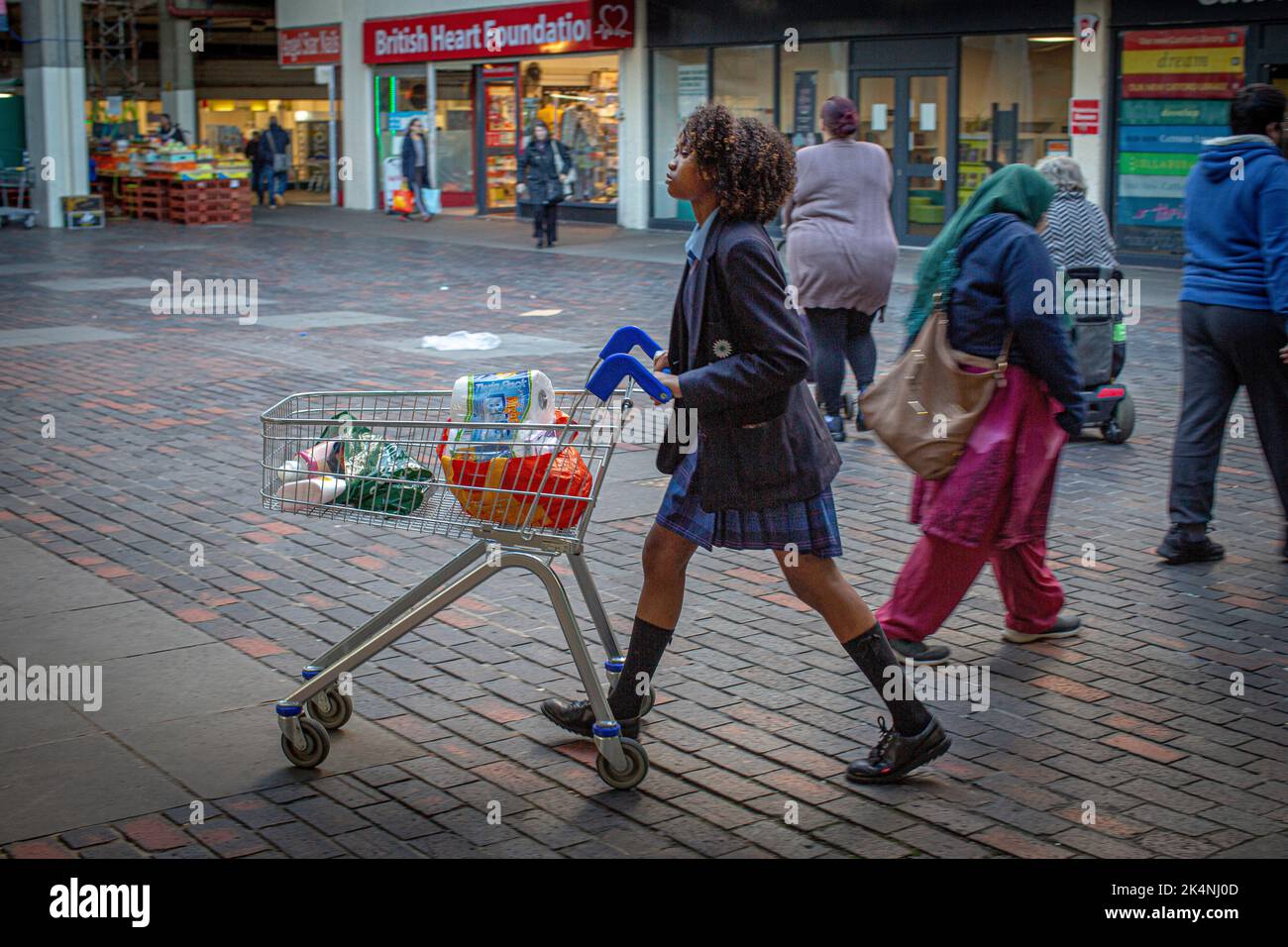 Londres, Royaume-Uni. Septembre 29 2022 . Girls waring école uniforme marche avec chariot à provisions au centre commercial Catford, Londres. Banque D'Images