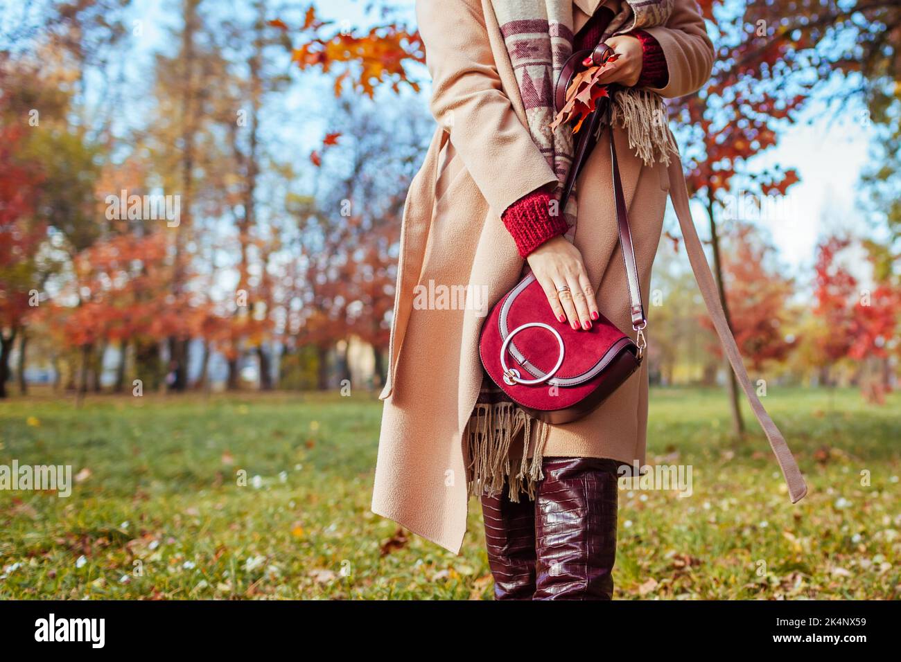Gros plan sur un élégant sac à main rouge bordeaux aux mains des femmes.  Femme marchant dans le parc d'automne. Tenue tendance automnale pour femme  Photo Stock - Alamy
