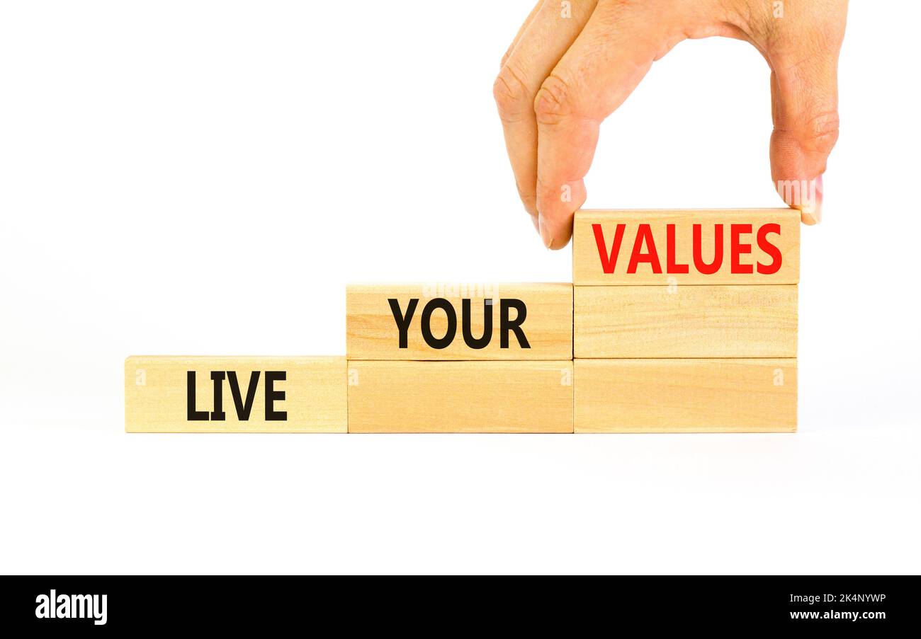 Vivez le symbole de vos valeurs. Concept mots Live vos valeurs sur des blocs de bois. Main d'homme d'affaires. Magnifique table blanche fond blanc. Affaires, psycolo Banque D'Images