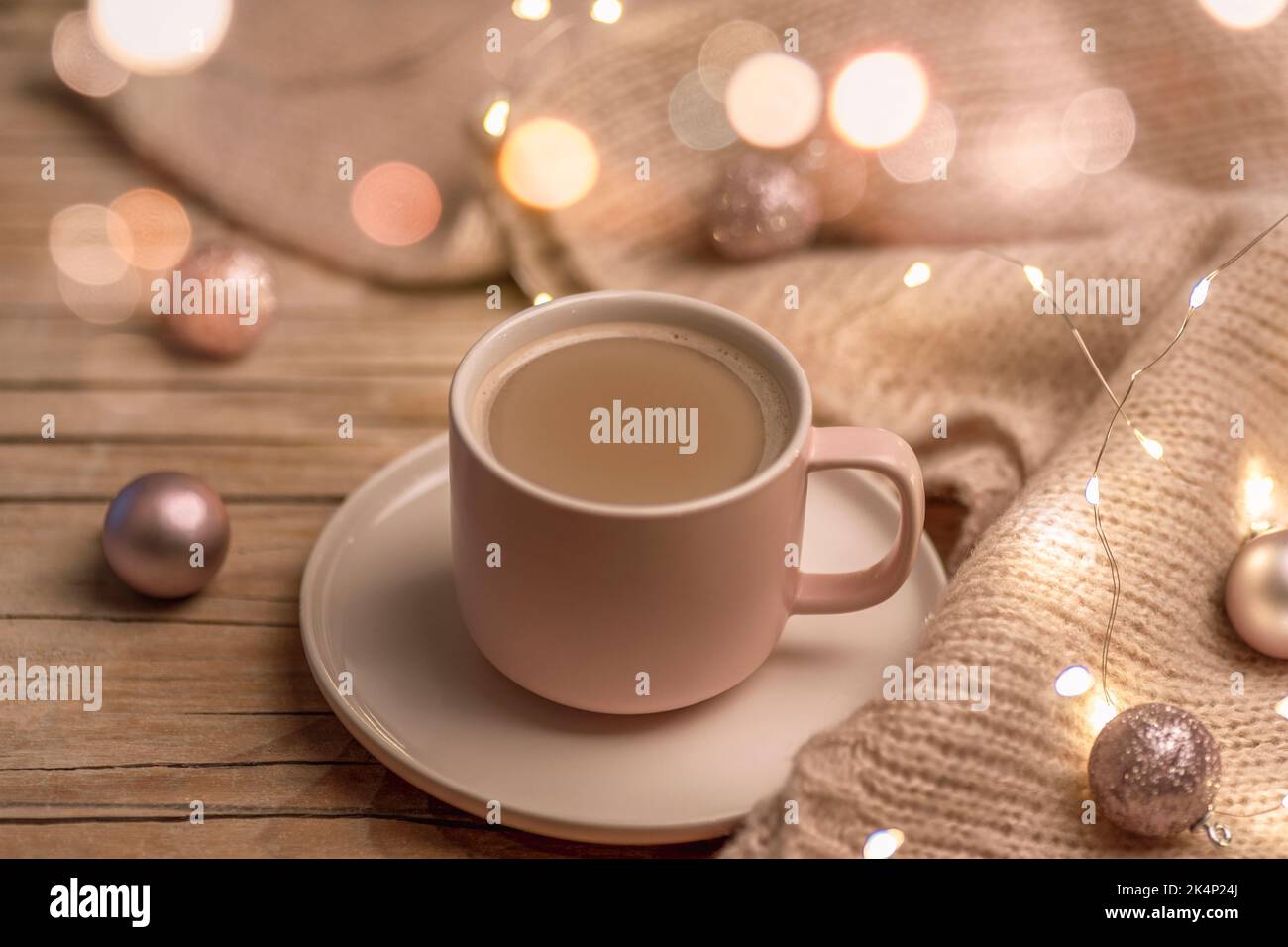 Une tasse de boisson chaude et des boules de Noël sur un pull en maille, décoré avec des guirlandes lumineuses. Concept vacances d'hiver. Banque D'Images