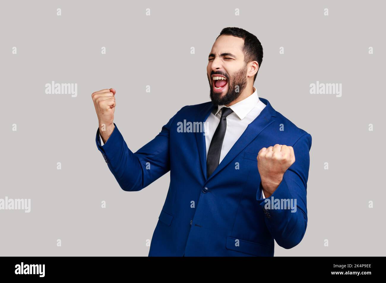 Homme barbu montrant oui geste et criant célébrant sa victoire, le succès, les rêves deviennent réalité, l'euphorie, portant le costume de style officiel. Prise de vue en studio isolée sur fond gris. Banque D'Images Homme barbu montrant oui geste et criant célébrant sa victoire, le succès, les rêves deviennent réalité, l'euphorie, portant le costume de style officiel. Prise de vue en studio isolée sur fond gris. Banque D'Images