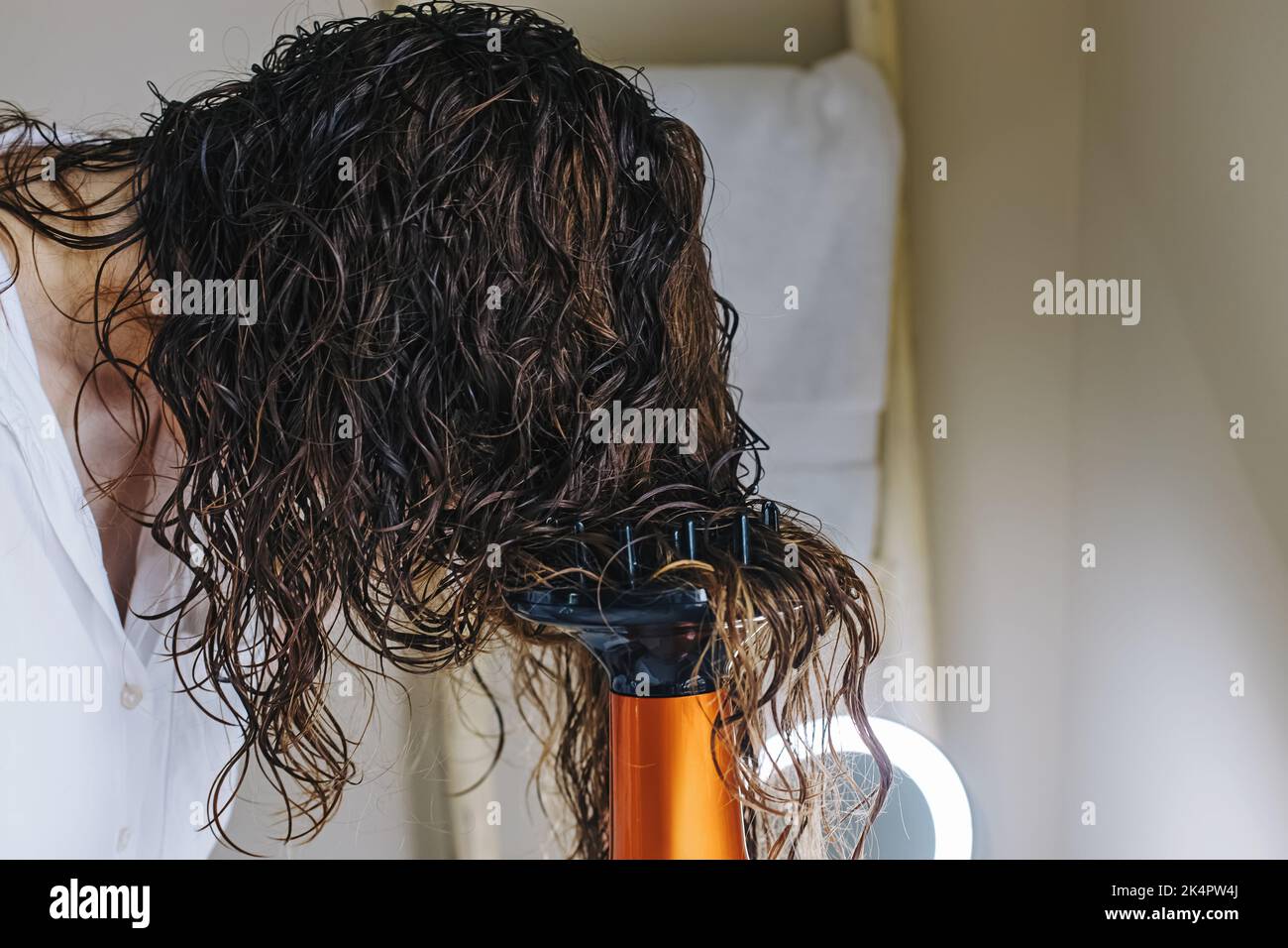 Femme diffuse ses cheveux avec un sèche-cheveux. Séchage des cheveux selon une méthode de coiffage en courbure Banque D'Images
