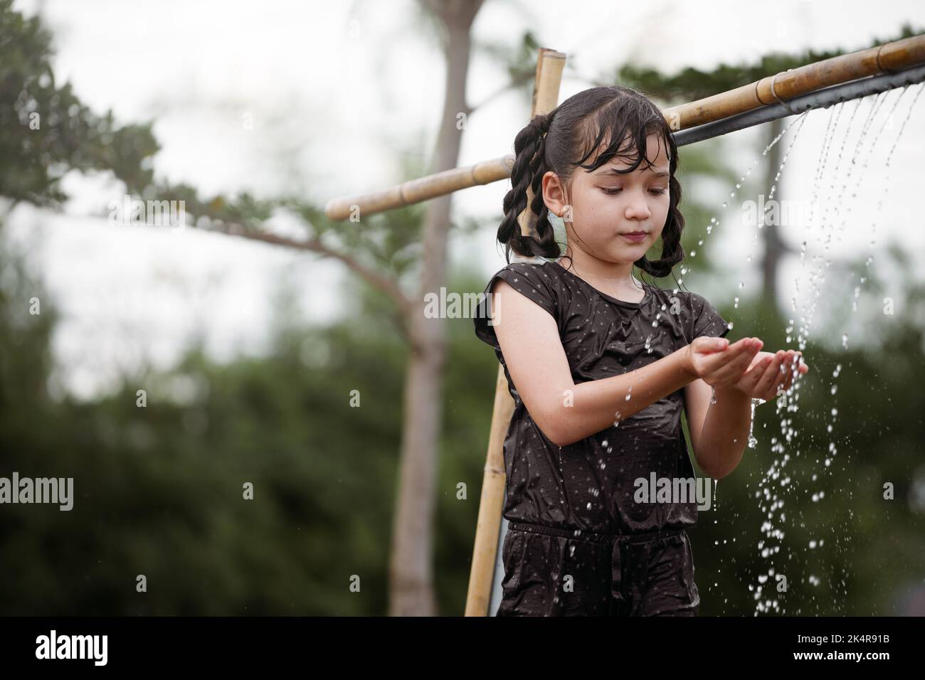 Enfant fille a plaisir à jouer dans l'eau à l'extérieur. Banque D'Images