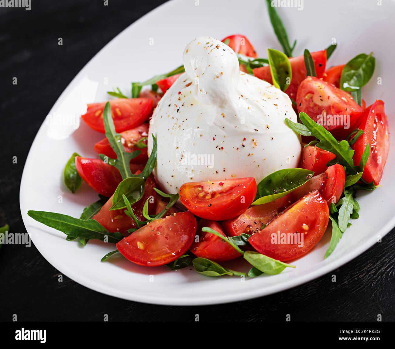 Salade avec tomates et fromage burrata avec basilic et huile d'olive sur l'assiette. Cuisine italienne. Banque D'Images