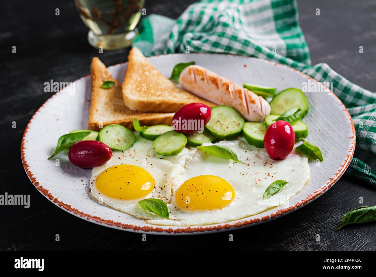 Petit-déjeuner anglais - oeufs frits, saucisses, concombre et toasts. Cuisine américaine. Banque D'Images