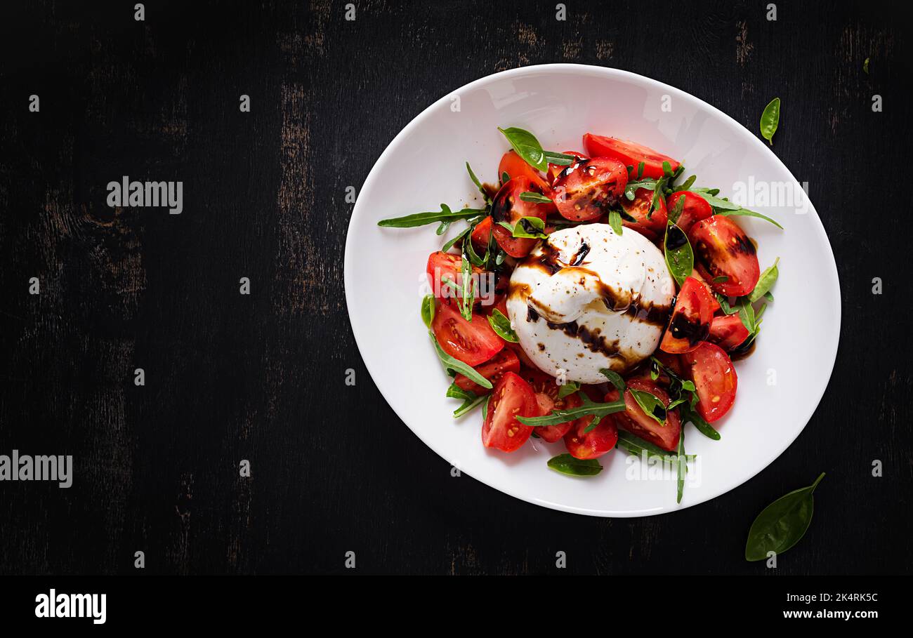 Salade avec tomates et fromage burrata avec basilic et huile d'olive sur l'assiette. Cuisine italienne. Vue de dessus, plan d'appartement Banque D'Images