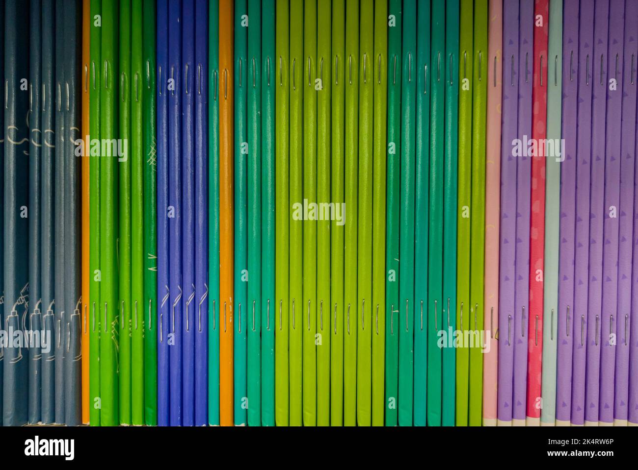 Carnets colorés sur l'étagère de la librairie. Beaucoup de livres avec des couvertures brillantes dans un tas. Élément design, texture papier et cuir. Banque D'Images