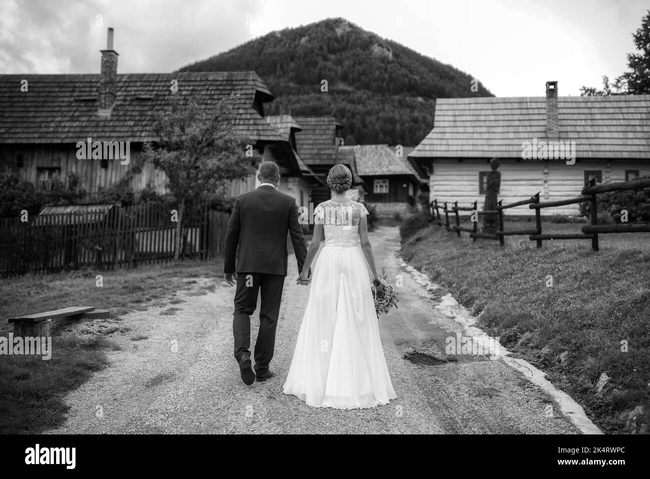 une mariée et un marié tenant les mains et marchant ensemble à travers la campagne. photographie en noir et blanc Banque D'Images