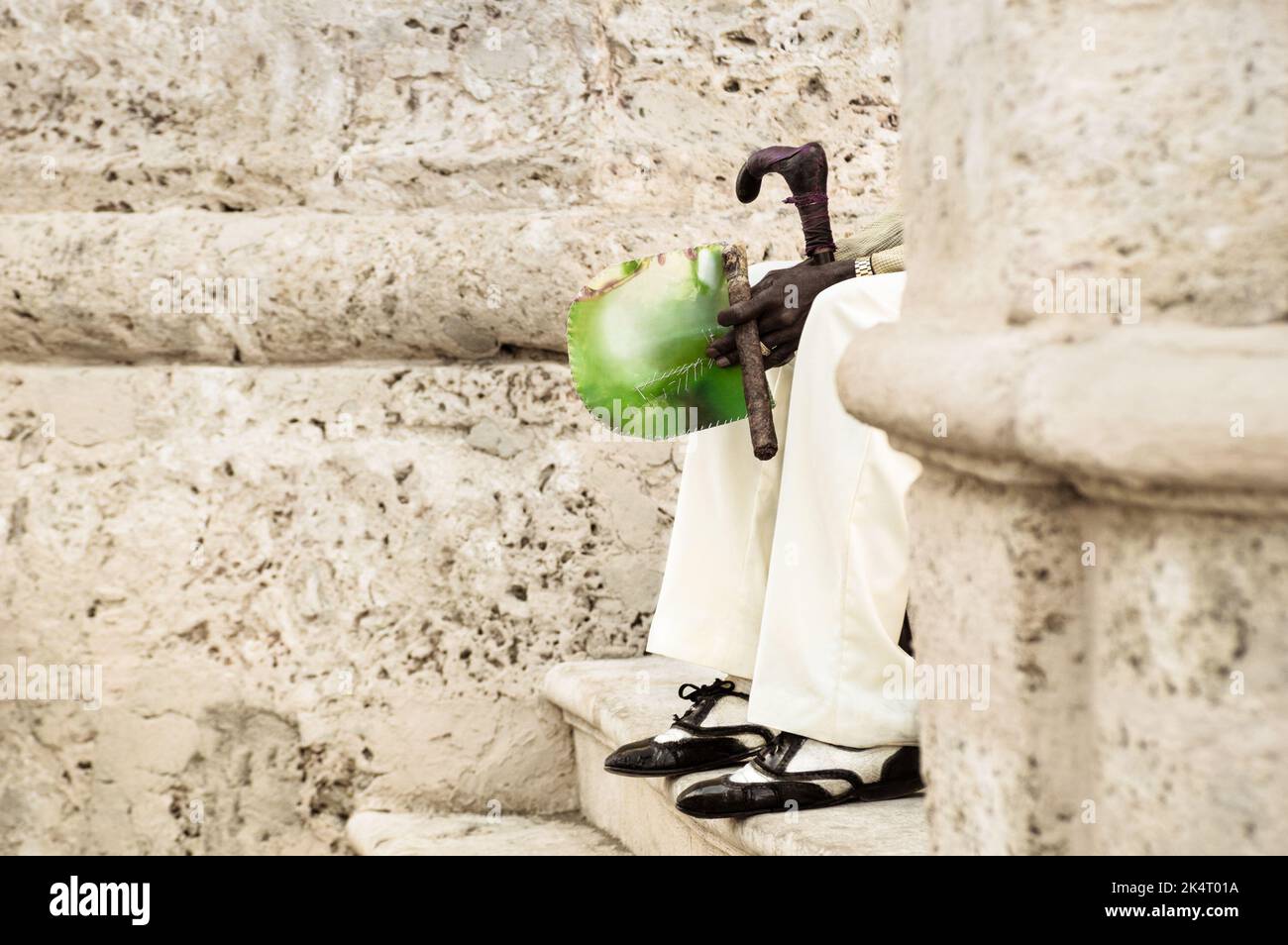 Détail d'une personne méconnaissable avec un cigare cubain assis dans les escaliers de la vieille ville de la Havane à Cuba - homme indigène portant des vêtements traditionnels et un accès Banque D'Images