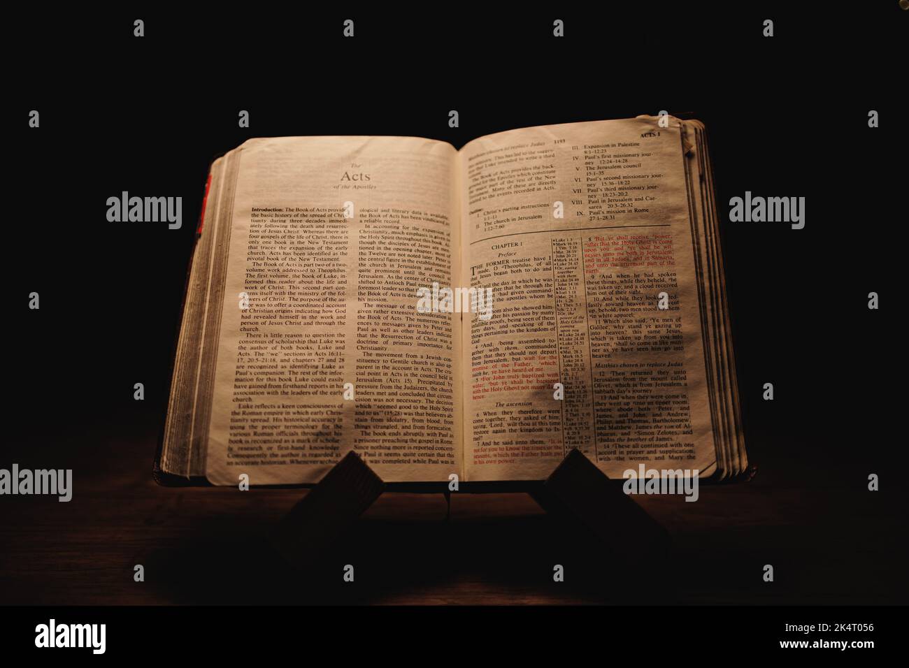 Un gros plan d'une vieille Bible historique ouverte sur les pages actes exposées dans une pièce sombre Banque D'Images