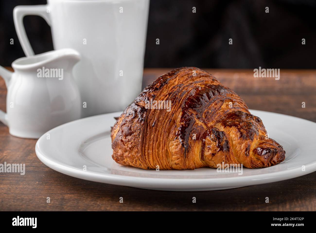 Croissant avec café à côté sur une table en bois Banque D'Images