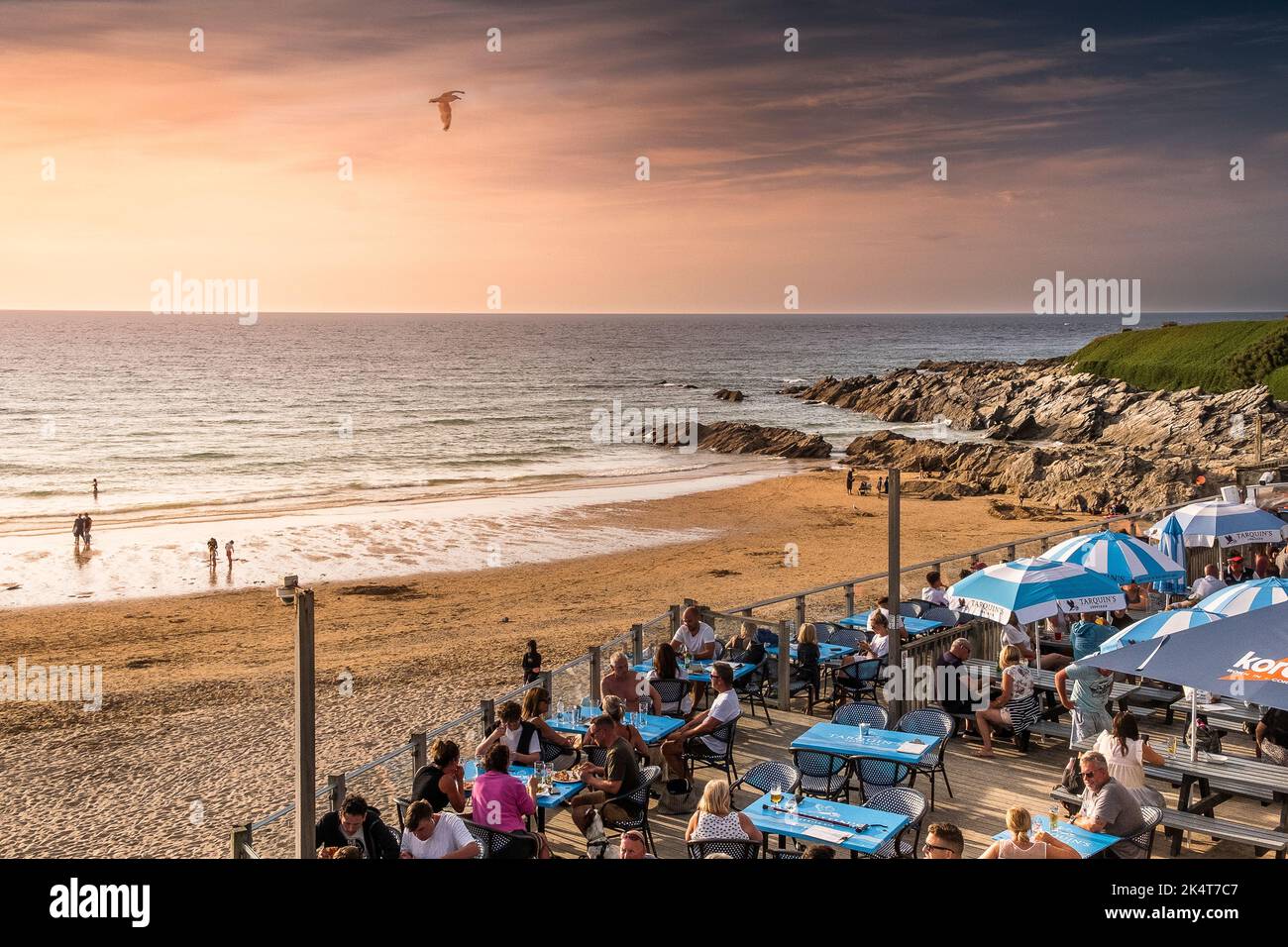 Vacanciers profitant de la lumière intense du soleil en soirée assis sur la zone de salon extérieure du Fistral Beach Bar à Newquay, en Cornouailles, au Royaume-Uni, en E Banque D'Images